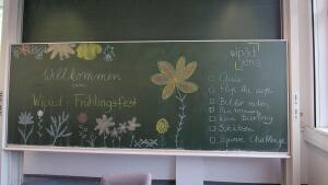 Hier sieht man eine Tafel mit der Aufschrift: "Willkommen zum WiPäd-Frühlingsfeste" und Spielen.