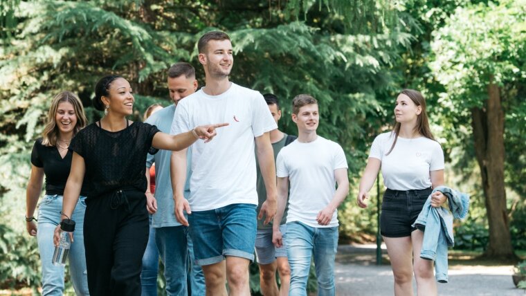 Eine Gruppe Studierender läuft gut gelaunt durch den Botanischen Garten.